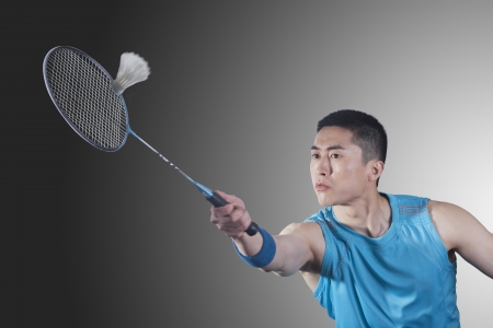 Young man playing badminton, hittingの写真素材