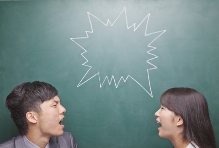 Two young people yelling at each other in front of blackboardの写真素材