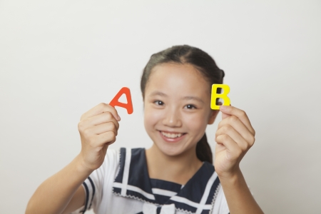 Girl smiling and holding plastic letters, Studioの写真素材