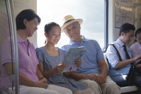 Granddaughter with grandparents sitting in the subway and looking at the mapの写真素材