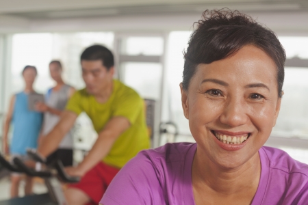 Woman smiling and exercising on the exercise bikeの写真素材