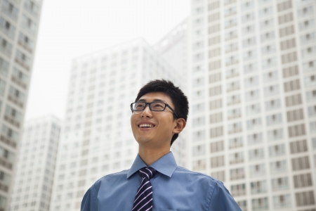 Young businessman smiling and looking at the skyの写真素材