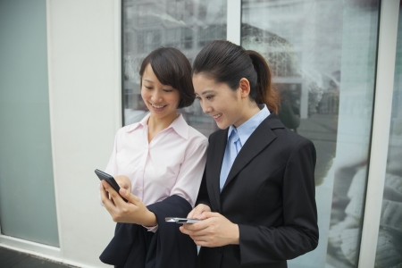 Young businesswomen looking at their cell phonesの写真素材