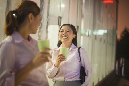 Young businesswomen smiling and drinking coffee outdoorの写真素材