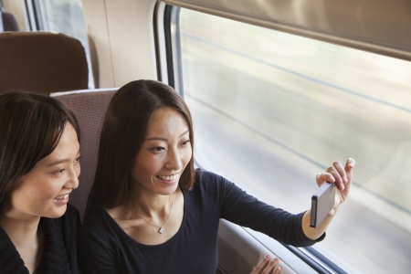 Two Friends Taking a Picture Out the Train Windowの写真素材