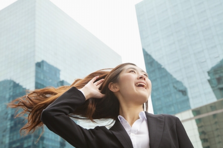 Young Businesswoman with hair blowing in the wind, outdoors, Beijingの写真素材