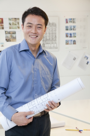 Businessman standing with stuck of papers in the office, portraitの写真素材