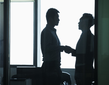 Businessmen shaking hands in officeの写真素材
