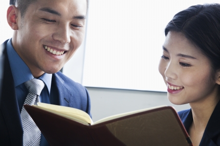 Co-workers checking agenda in officeの写真素材