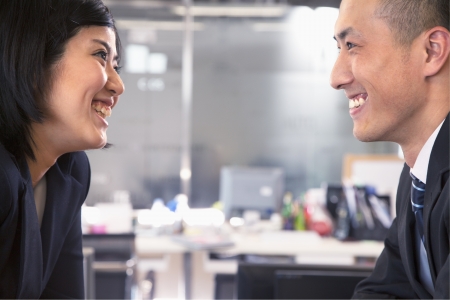Two business people smiling and laughing face to faceの写真素材