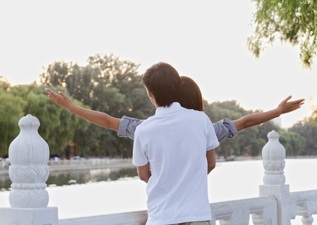 Young Couple with Arms Outstretched by a Lakeの写真素材