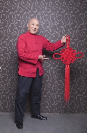 Portrait of Senior Man in Traditional Chinese Clothing holding Tied Knotの写真素材