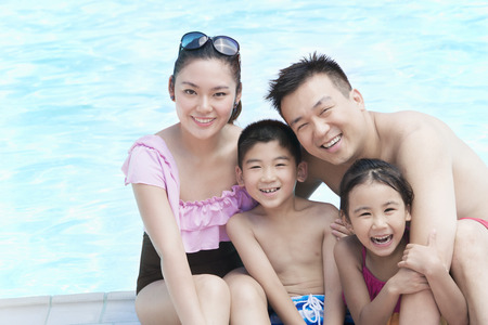 Family portrait, mother, father, daughter, and son, smiling by the pool の写真素材