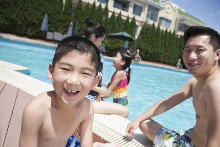 Cute little boy and his family playing in the poolの写真素材
