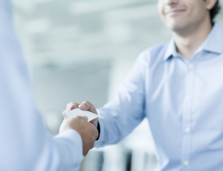 Close up of two businessmen exchanging business cardsの素材