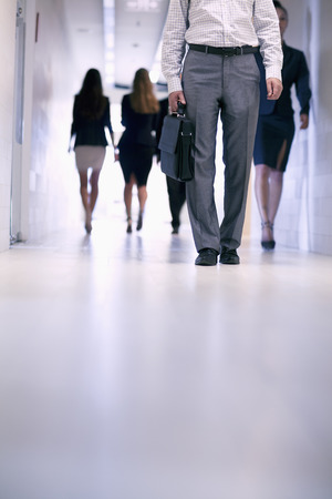 Low view of people walking down the corridor in an office buildingの写真素材