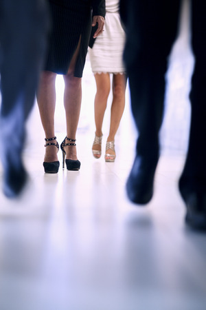 Low view of people walking down the corridor in an office building, focus on high heelsの写真素材