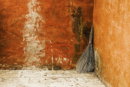 Broom leaning against the wall in a rural courtyardの写真素材