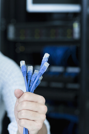 Close up of young man holding a bunch of computer cablesの写真素材