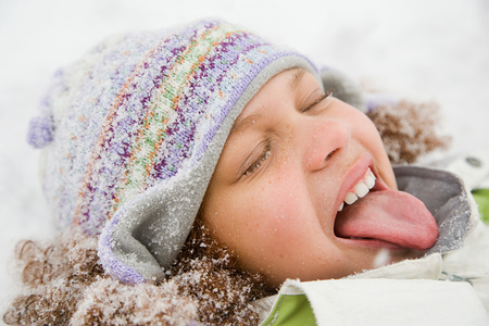 Girl in snow sticking out tongueの写真素材