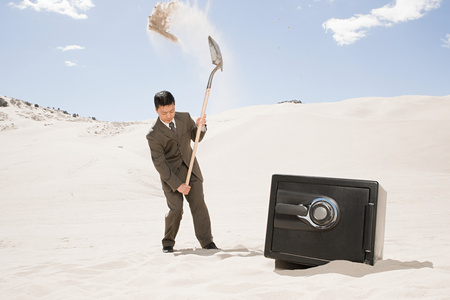 Man digging by safe in desertの写真素材
