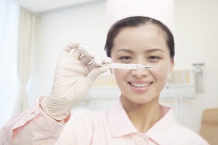 Young Nurse Holding Thermometer, Close-Upの写真素材