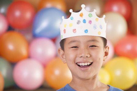Birthday Boy Wearing a Crown in Front of Balloonsの写真素材