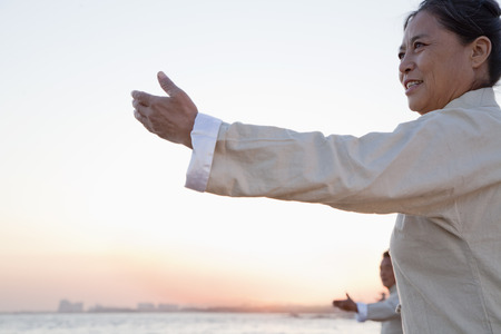 Two older people practicing Taijiquan on the beach at sunset, Chinaの写真素材