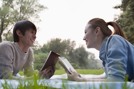 Teenage couple reading books in the park の写真素材