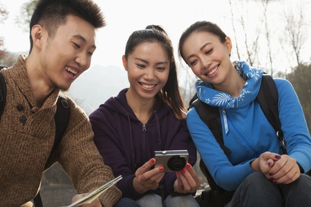 Friends looking at the picture on the screen of digital camera の写真素材