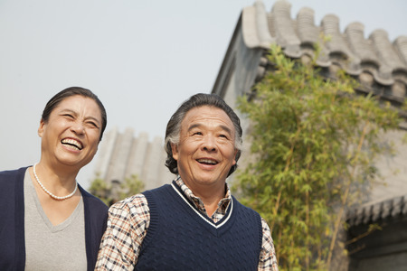 Happy senior couple walking outdoors by traditional building in Beijingの写真素材