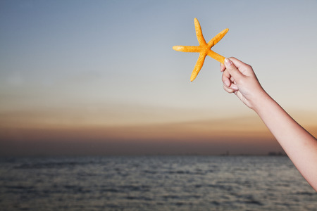Teenage girl holding starfish, close up on human armの写真素材