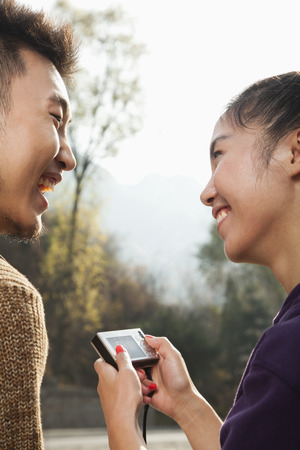 Young couple smiling, woman holding digital cameraの写真素材
