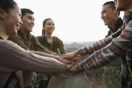 Group of young people smiling and holding hands together on the stone 