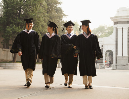 Young Graduates Walking Across Campusの写真素材