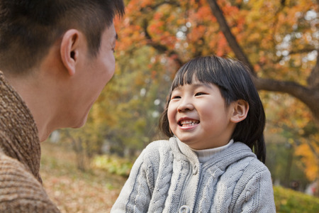 Father and daughter looking at each other in the park, autumnの写真素材