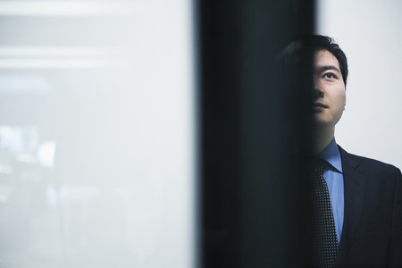 Businessman standing and looking up parking garage, white backgroundの写真素材