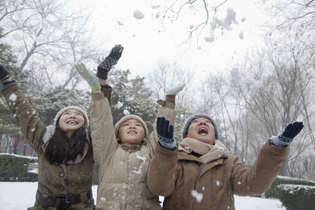 Family throwing snow into air in parkの写真素材