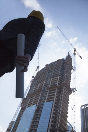 Architect holding blue print and looking up, low angle viewの写真素材