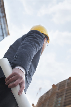 Architect holding blue print and looking up, low angle viewの写真素材