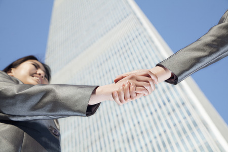 Close up of two business people shaking hands by the china world trade center in Beijingの写真素材