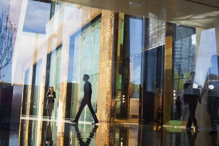 Business People walking through the lobby of an office building on the other side of a glass wallの写真素材