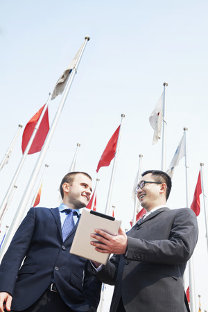 Two smiling business people talking and holding digital tabletの写真素材