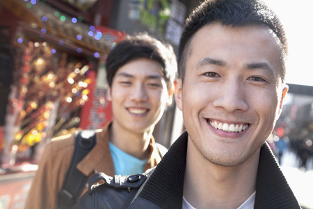Two young men with Chinese Architecture in background.の写真素材
