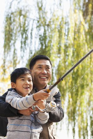Father and son fishing together at lakeの写真素材