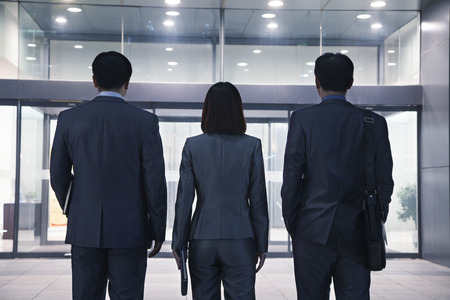 Three business people standing in a row, rear viewの写真素材