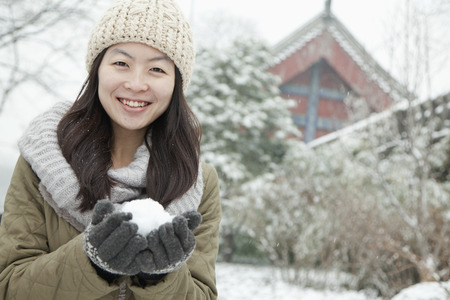 Woman Holding snowball outside in parkの写真素材