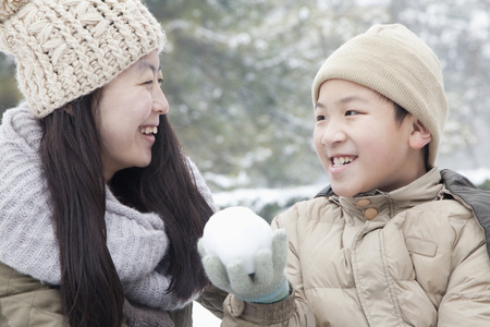 Mother helping son make snow ballの写真素材