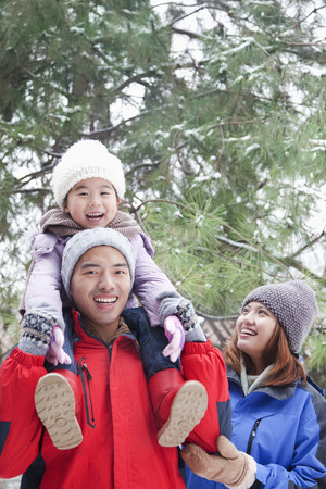 Father carrying daughter on shoulders in winterの写真素材