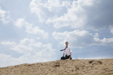Young businessman lost and walking through the desert, distant の写真素材